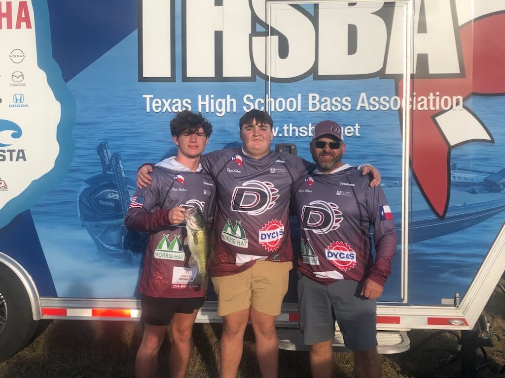 three bass club members holding fish in front of thsba trailer