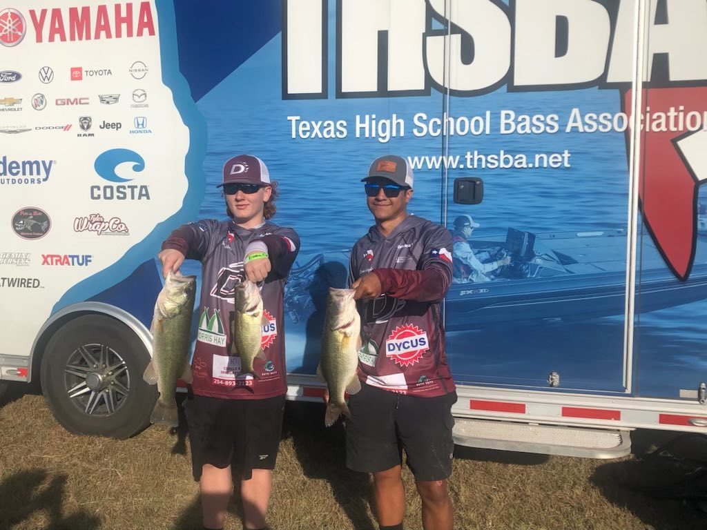 two bass club members holding fish in front of thsba trailer