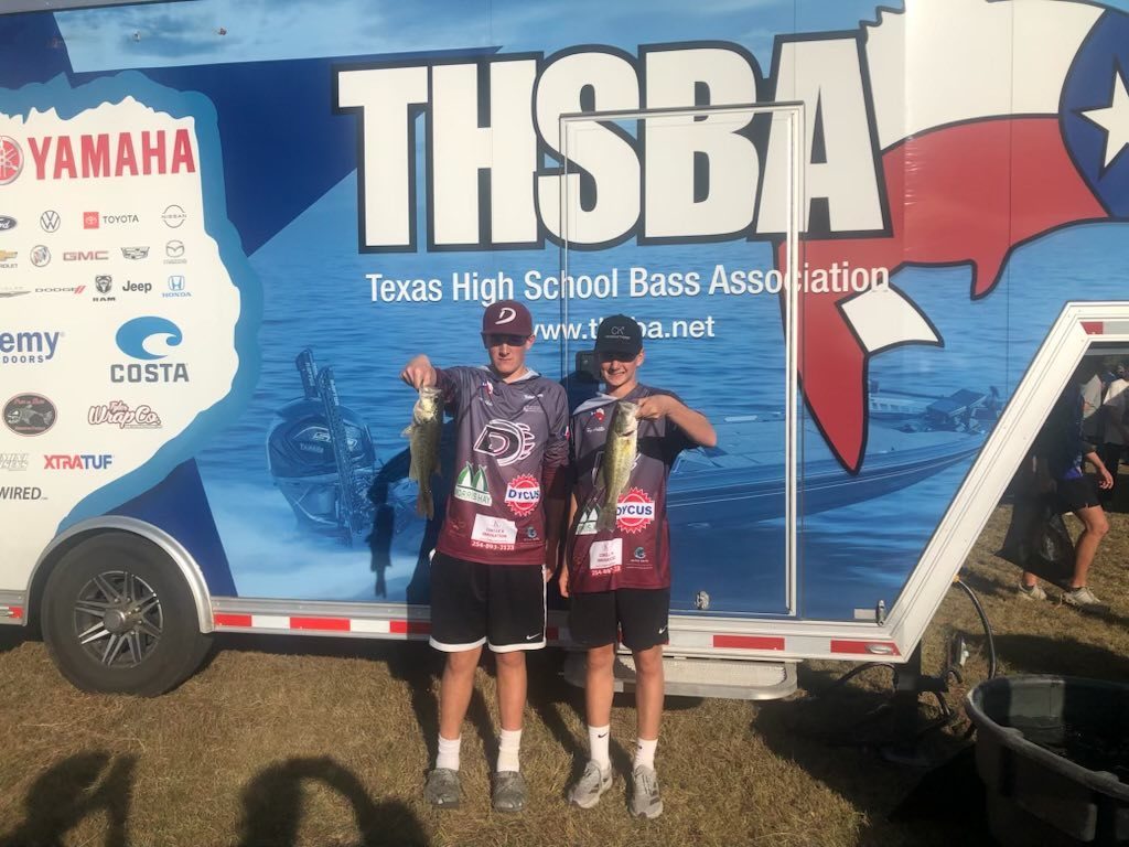 two bass club members holding fish in front of thsba trailer