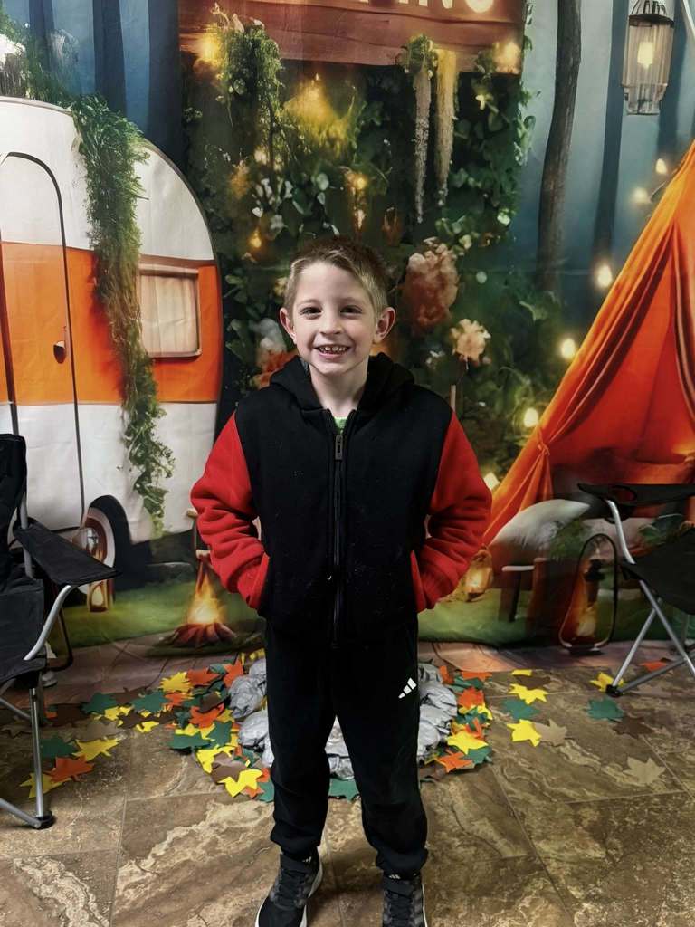one happy camper of the week standing in front of camping background