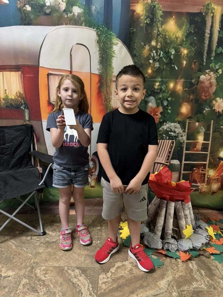 two happy campers of the week standing in front of camping backdrop