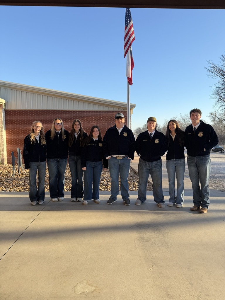 eight ffa members in front of flag pole at elementary entrance