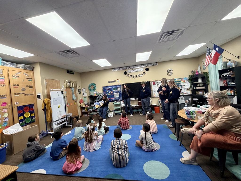 ffa members talking to elementary students who are sitting on rug in classroom