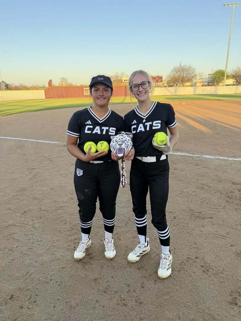 two softball players holding their homerun balls