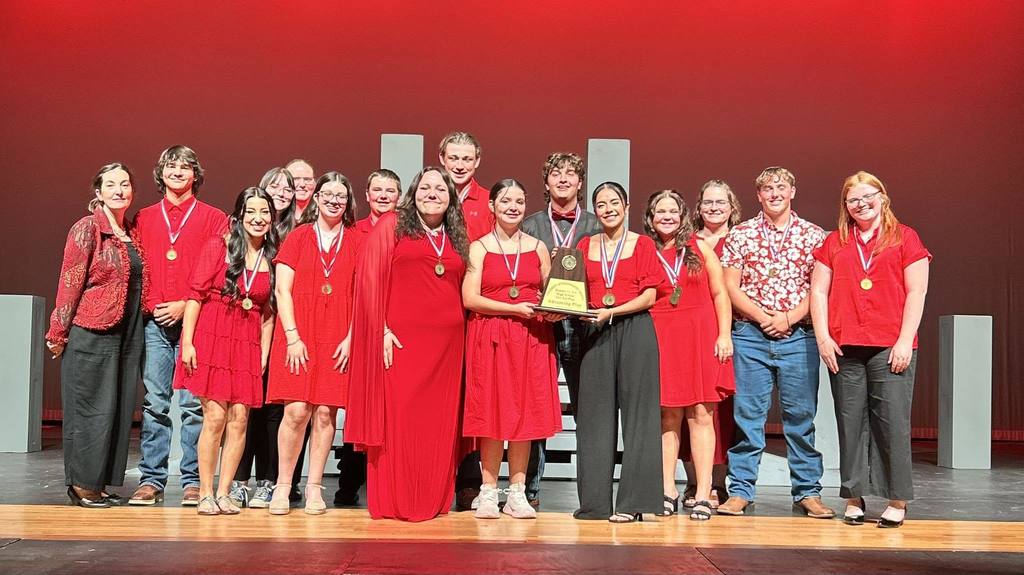 OAP group members on stage wearing medals and holding trophy