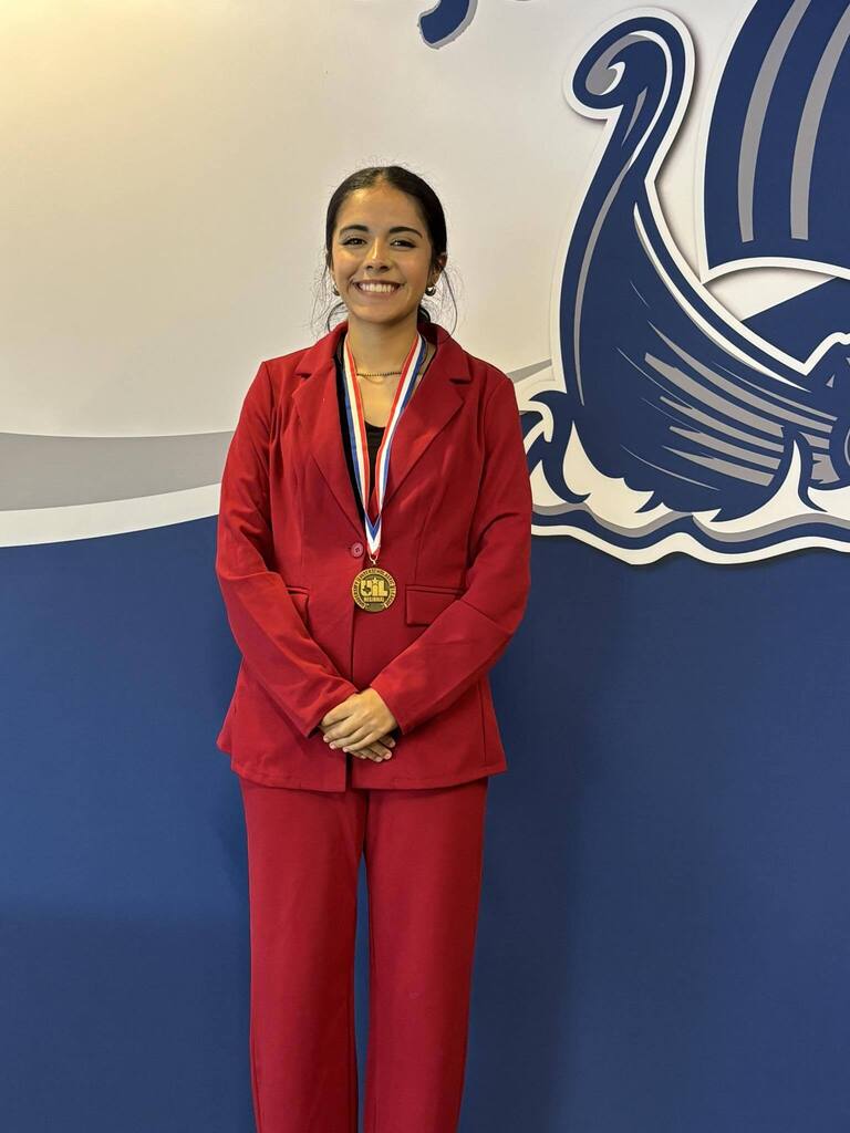 student dressed in red suit and wearing medal 
