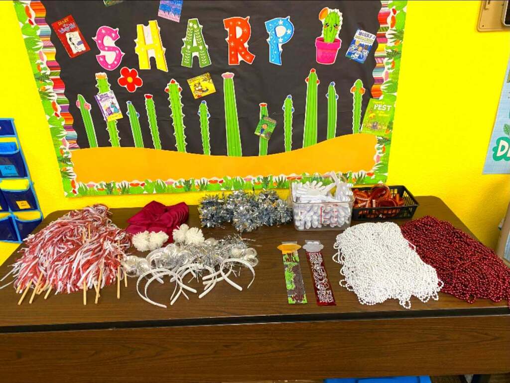 table full of spirit gear: streamers, headbands, ribbons, white and maroon beads, clappers, bows and bracelets