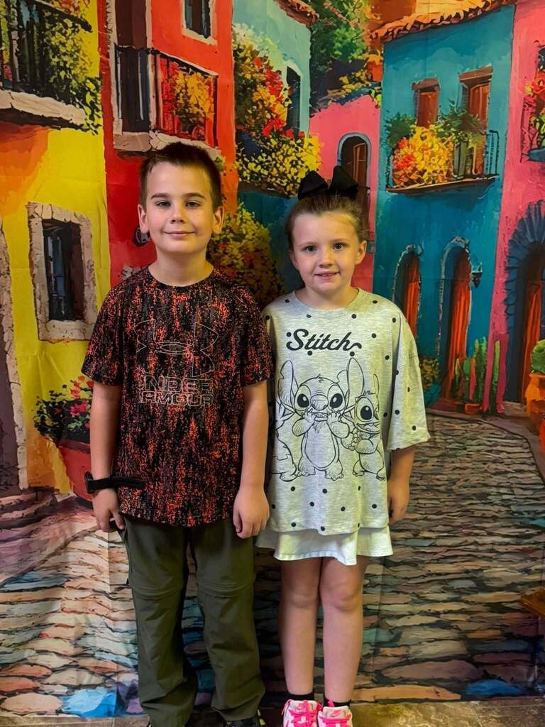 two star students of the week standing in front of decorative backdrop