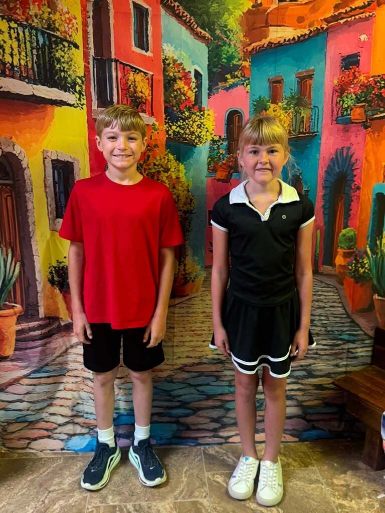 two star students of the week standing in front of decorative backdrop