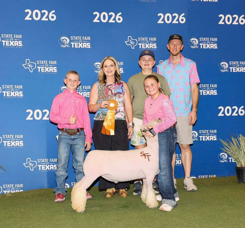 FFA student standing with show animal, three family members and lady holding yellow ribbon