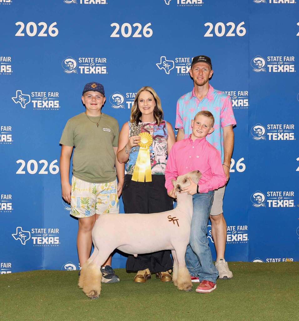FFA student standing with show animal, two family members and lady holding yellow ribbon