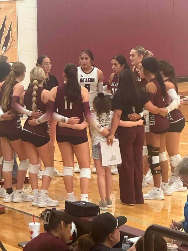 volleyball players in huddle with coach and young student