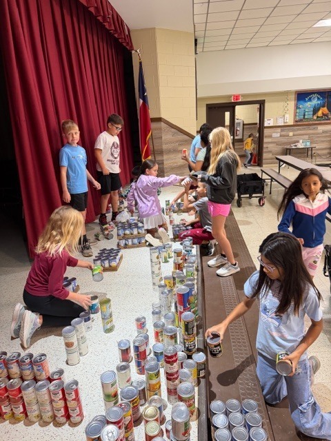 students working on making football field made of canned foods