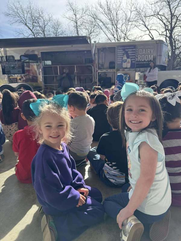 group of students sitting to guest speaker while two female students looking at camera