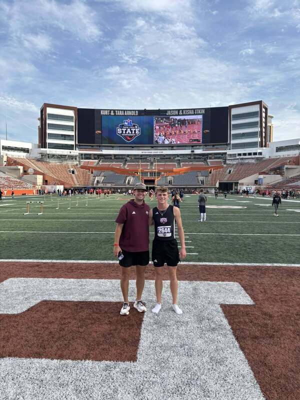 coach and athlete standing on field at UT Austin