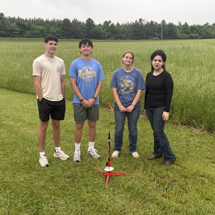 physics students standing with rocket