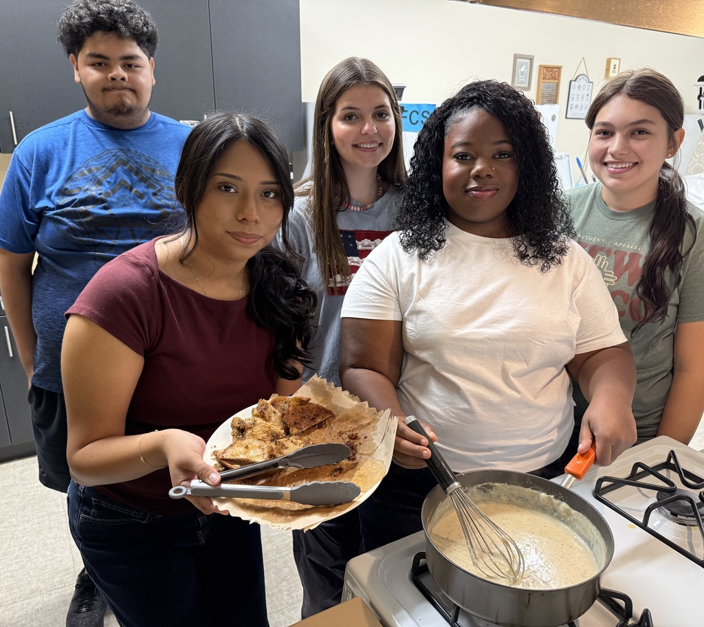Students with plate of pork chops and gravy in FACS class.