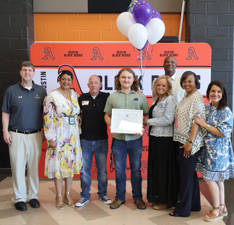 Senior Luke Brown stands with admin as he accepts scholarship to UNA this fall.