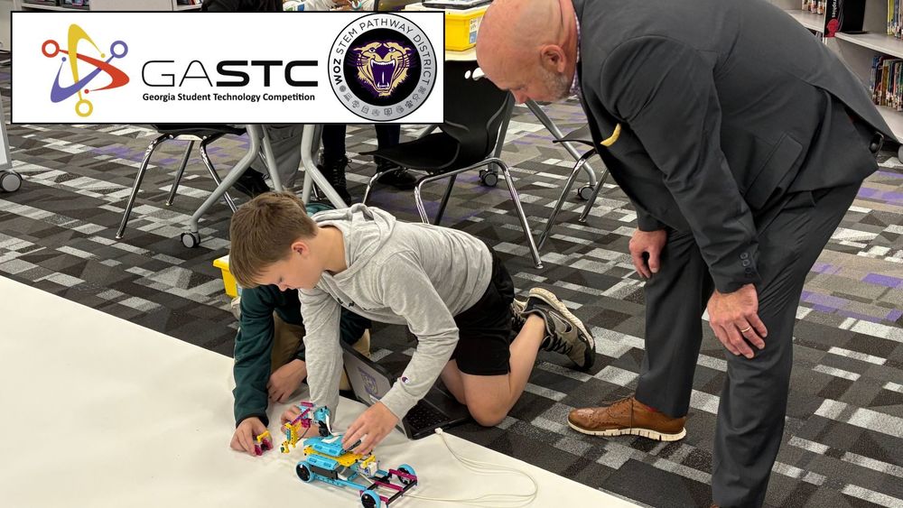 Superintendent Dr Boyd English digs into robotics with Austin and Andrew Gleeson at the Bainbridge Middle School Technology Competition