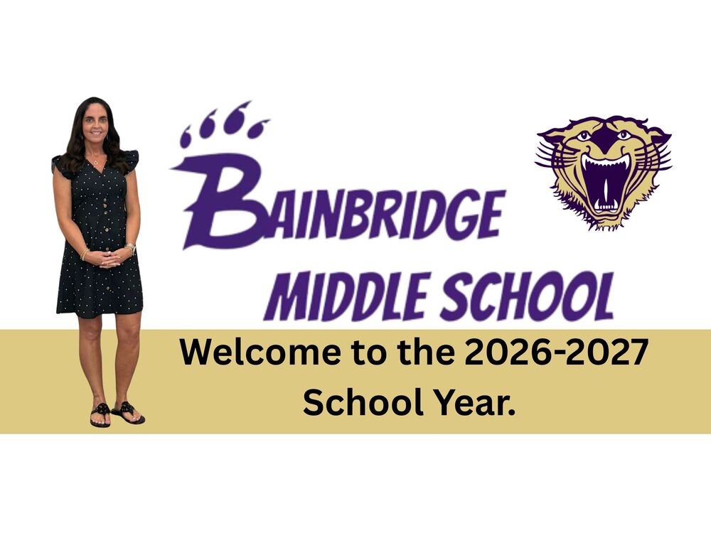 Principal standing beside the Bainbridge Middle School Logo