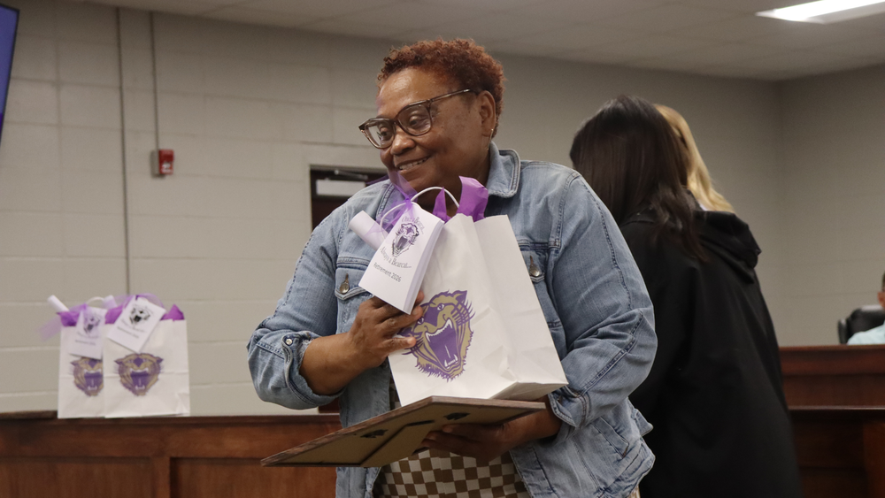 A school administrator presents a retirement plaque to a retiring staff member during a Decatur County Schools Board of Education meeting, recognizing her years of dedicated service.