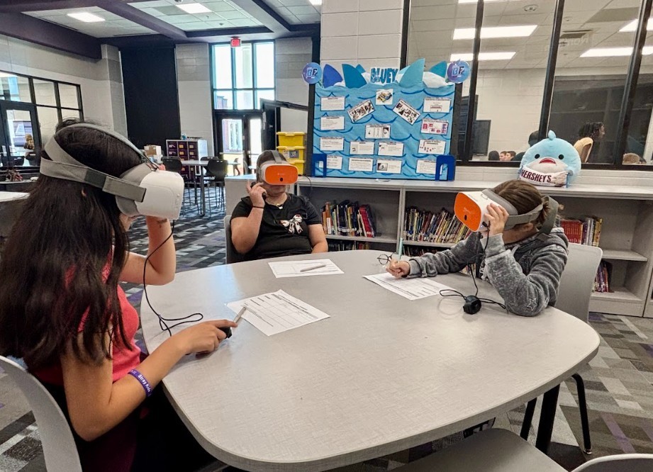 three studetns experiencing a VR experience and documenting their learning.