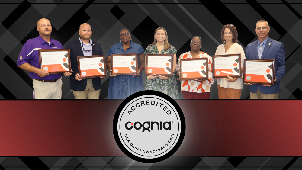 Seven Decatur County Schools representatives holding framed Cognia accreditation certificates, standing together in front of a Cognia Accredited logo background.