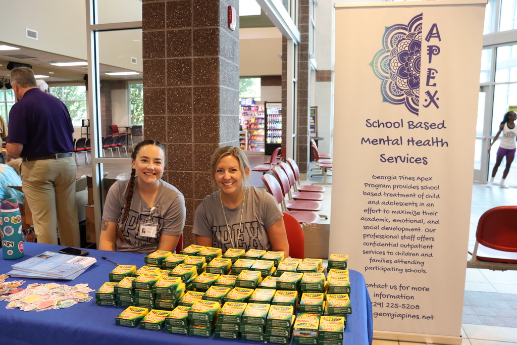 Representatives from Georgia Pines APEX smile behind a table stacked with crayon boxes.