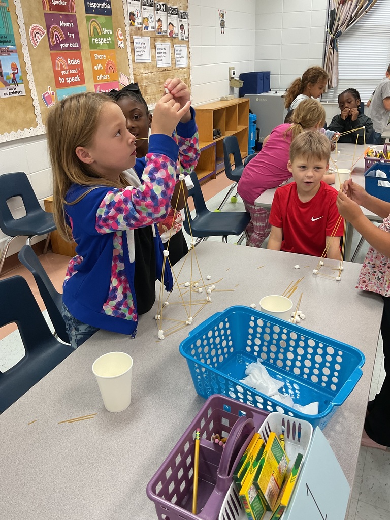 Elementary students build structures with spaghetti and marshmallows during a classroom STEM activity.