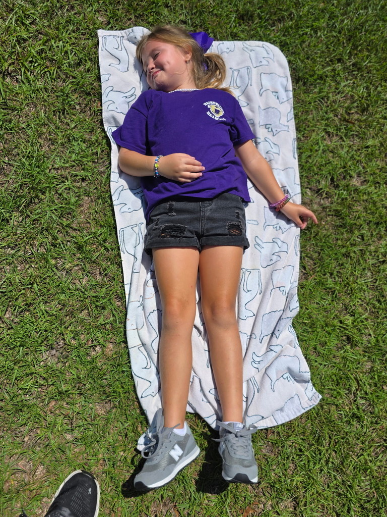 Student laying in the sun by the sand.