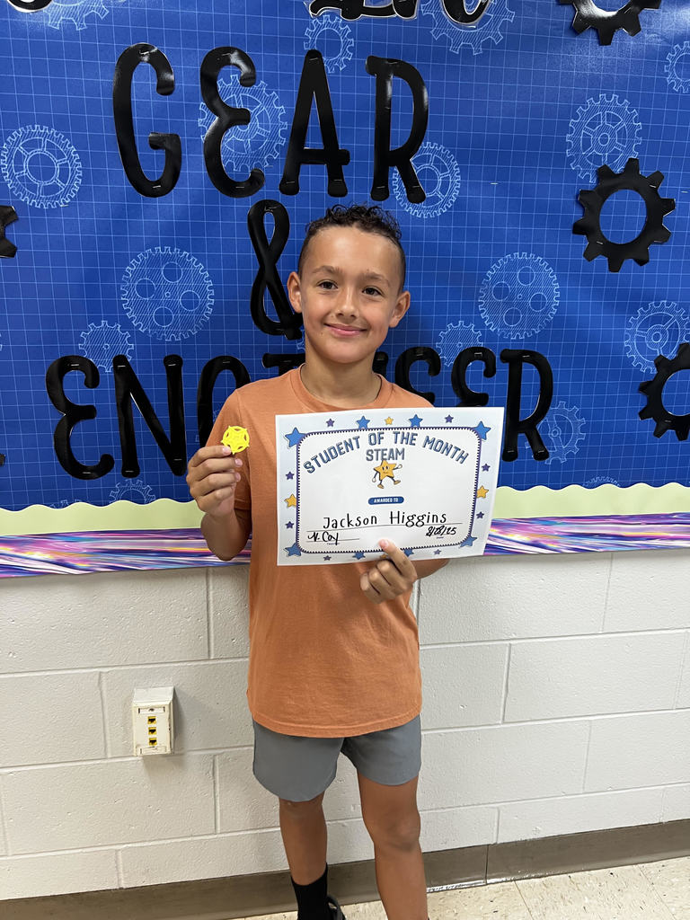 This image contains a picture of the student of month holding a certificate and a 3D token.