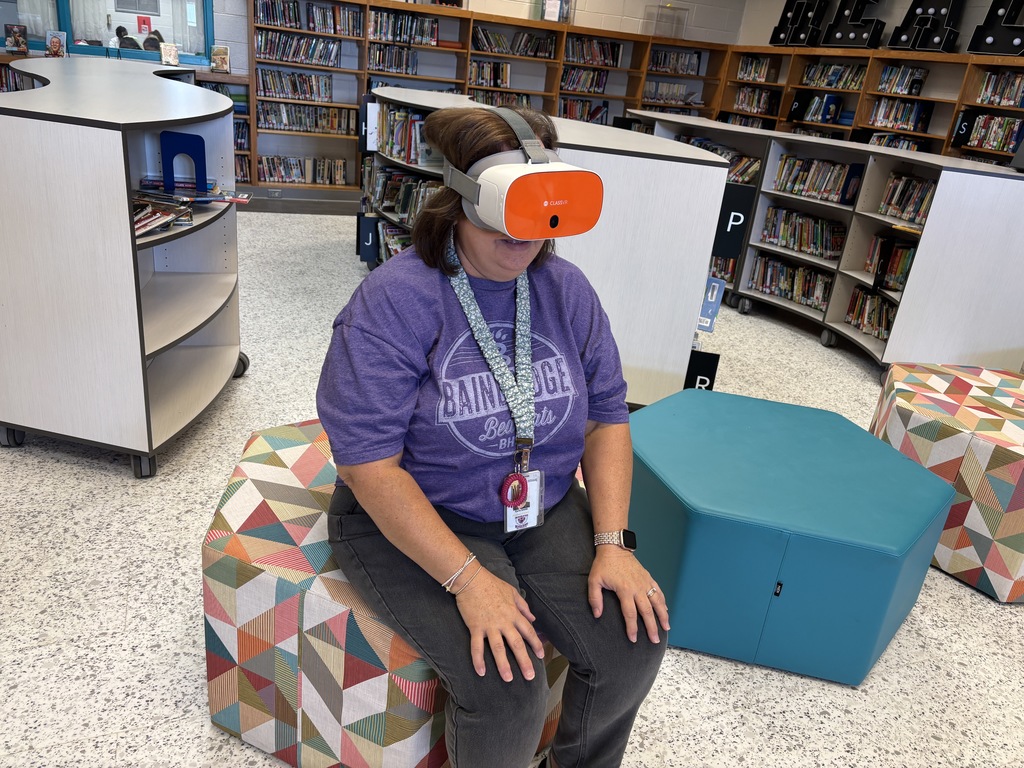 This image contains kids writing on a poster and looking inside of the VR Headsets.