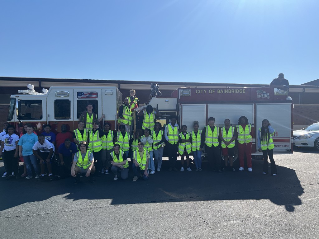 A large group photo of the Bainbridge High School Criminal Justice class posing in front of a fire truck, with some students sitting on the truck and others standing on the ground.