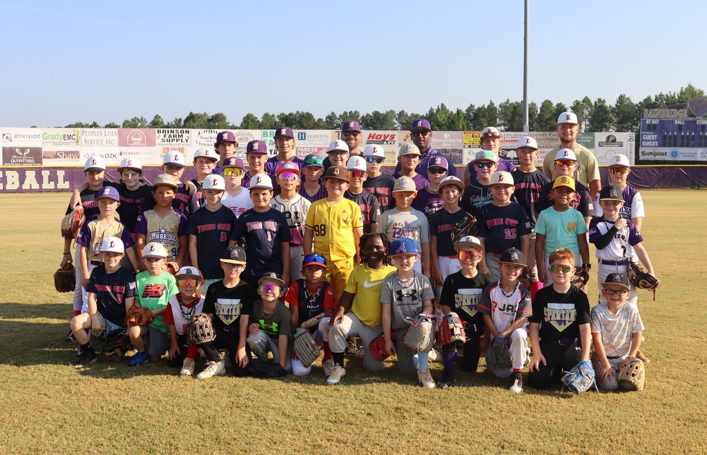 A large group photo of Future Bearcat Baseball Camp participants, including young athletes, high school players, and coaches, all smiling on the field.