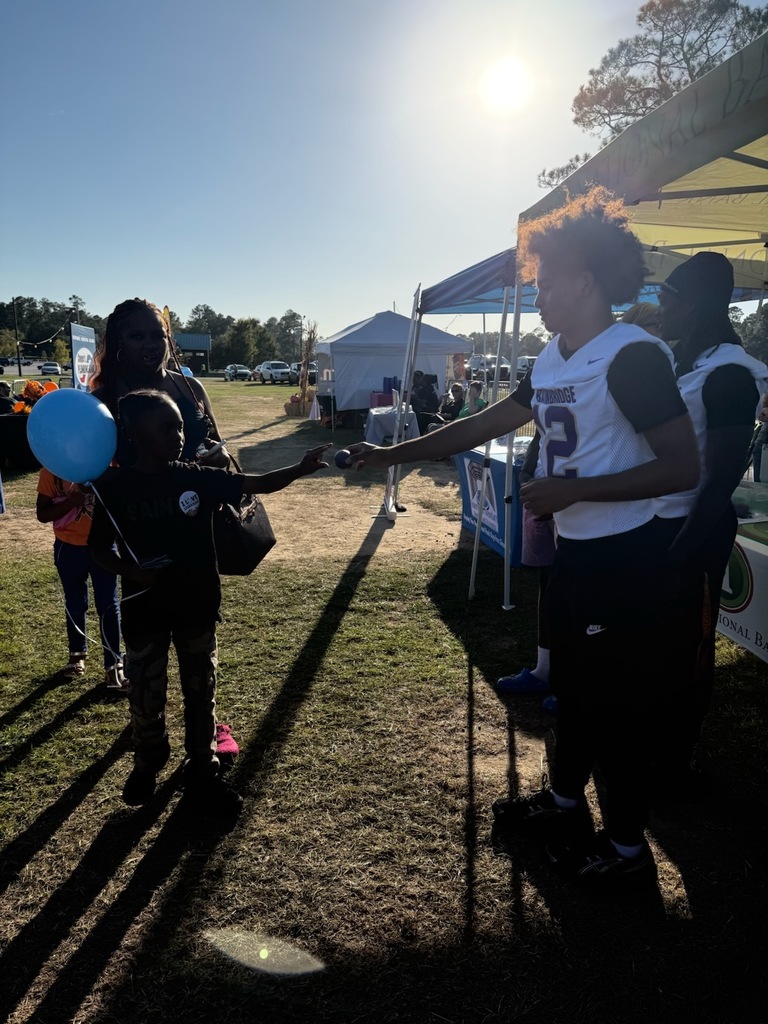 bainbridge high school football player passes mini signed football to child holding a balloon at the fair
