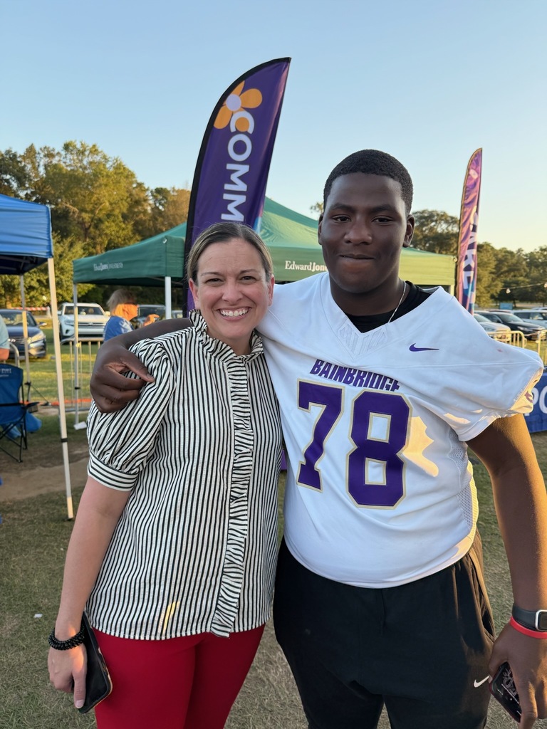 dcboe curriculum director christy cox stands hugging bhs footballl player and former student