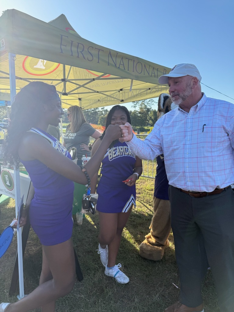 Superintendent Boyd English fist bumps a BHS cheerleader at vender table at the fair