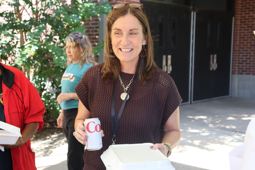 woman smiles in breeze way while holding a diet coke can