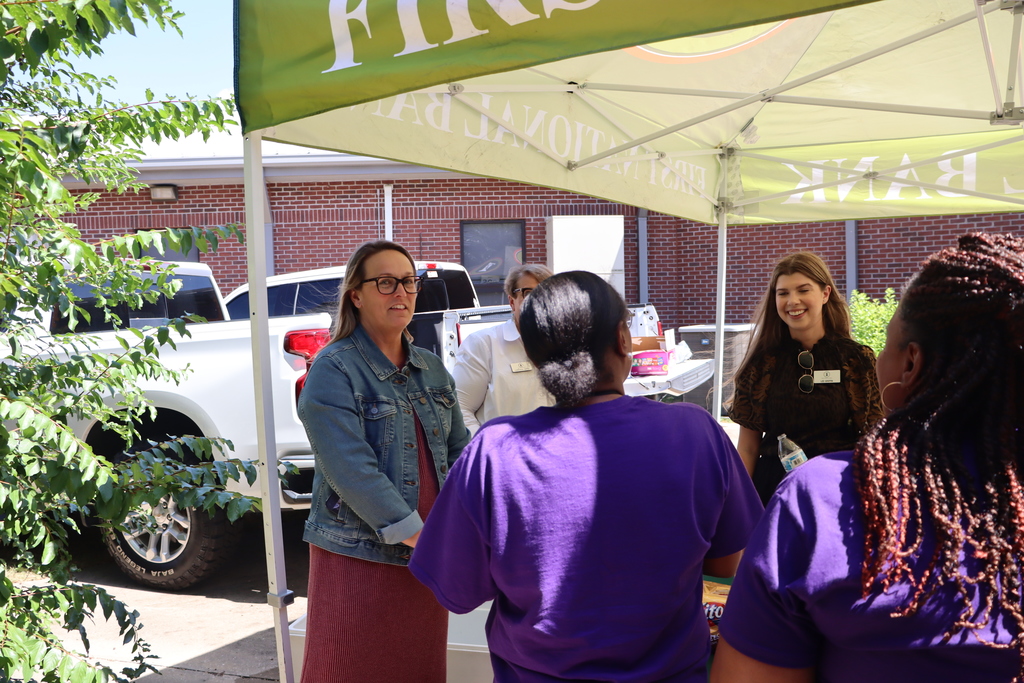 group gathers under an event tent smiling and serving teachers hamburgers