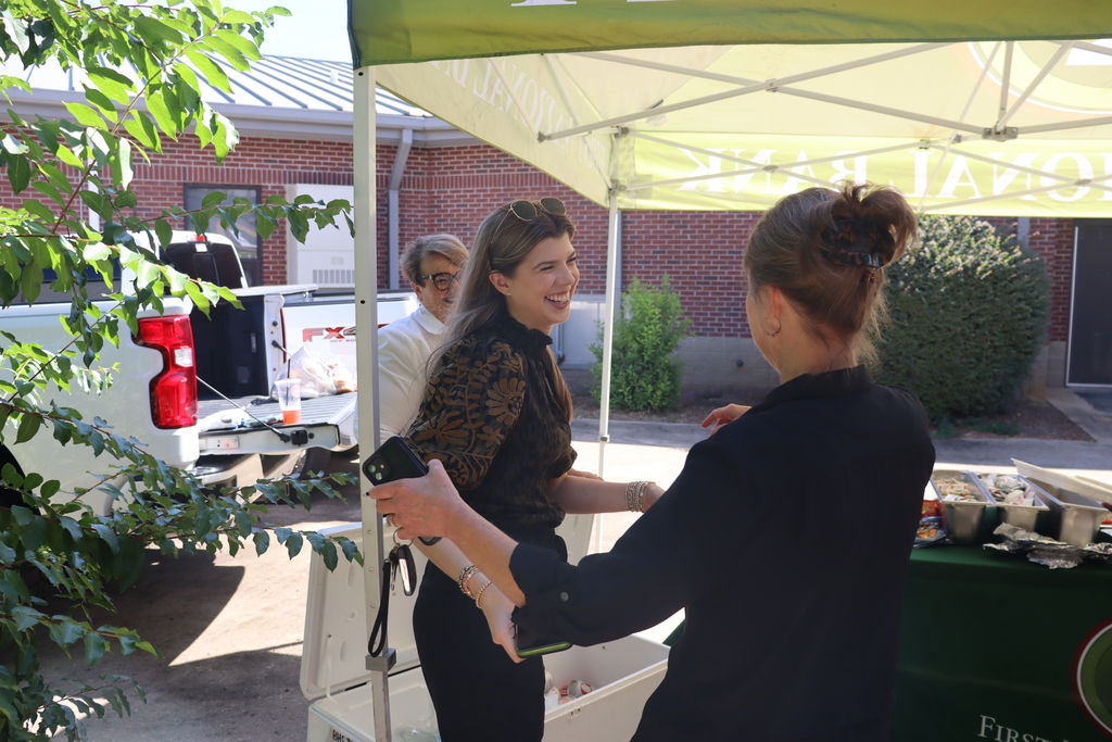 two woman hugging under a first national bank event tent