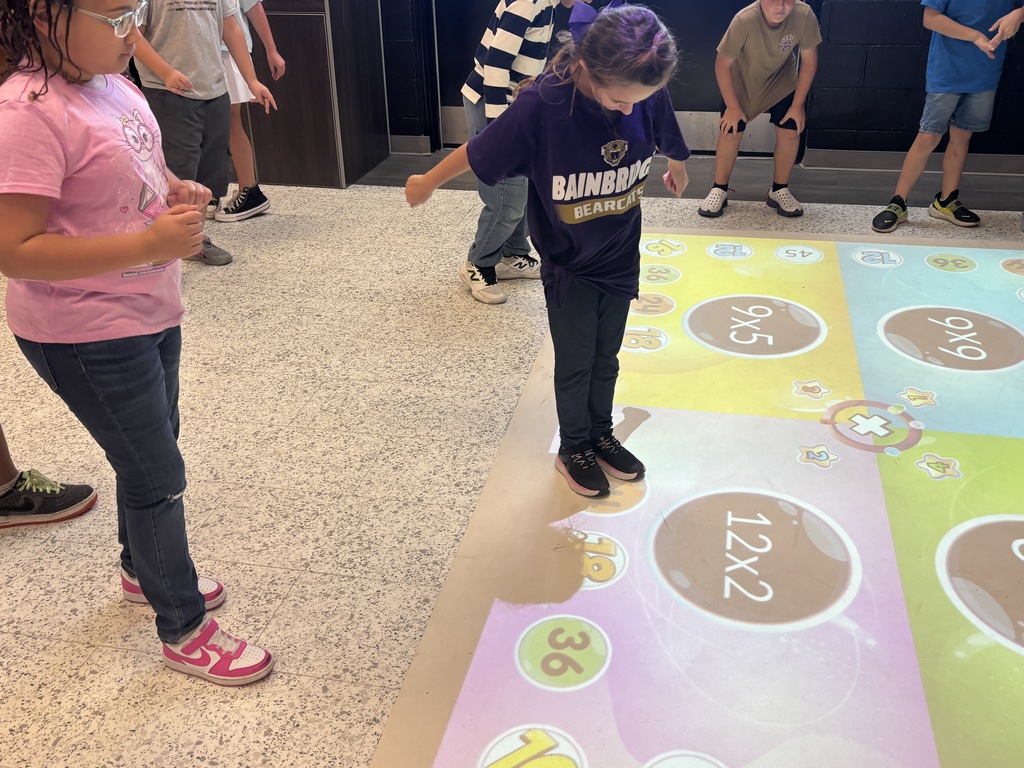 This image contains pictures of kids playing a math game on the active floor.
