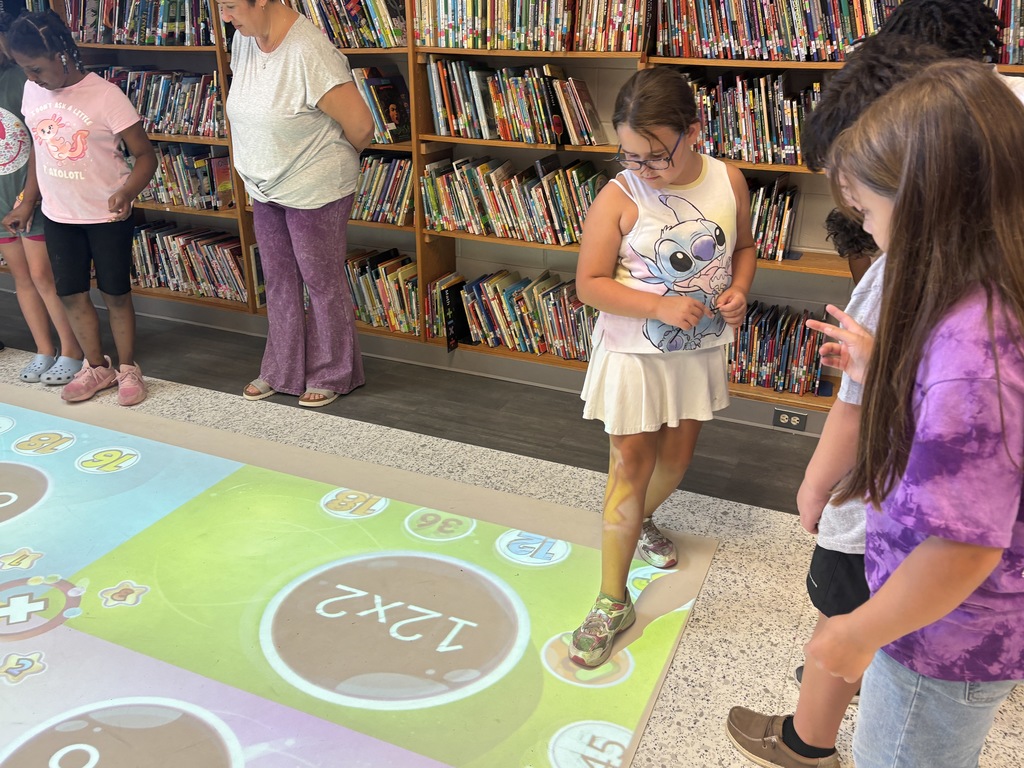This image contains pictures of kids playing a math game on the active floor.