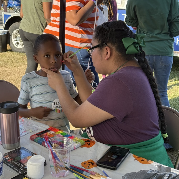 Bainbridge high school art student paints on child’s face in a tent at the fair