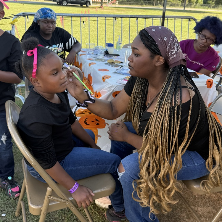 Bainbridge high school art student paints on child’s face in a tent at the fair