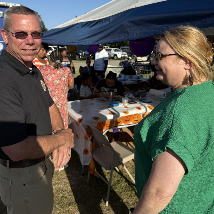 Hutto elementary school principal, Scott Morehouse and BHS art teacher Rebecca Cole stand talking in front of a tent at a fair