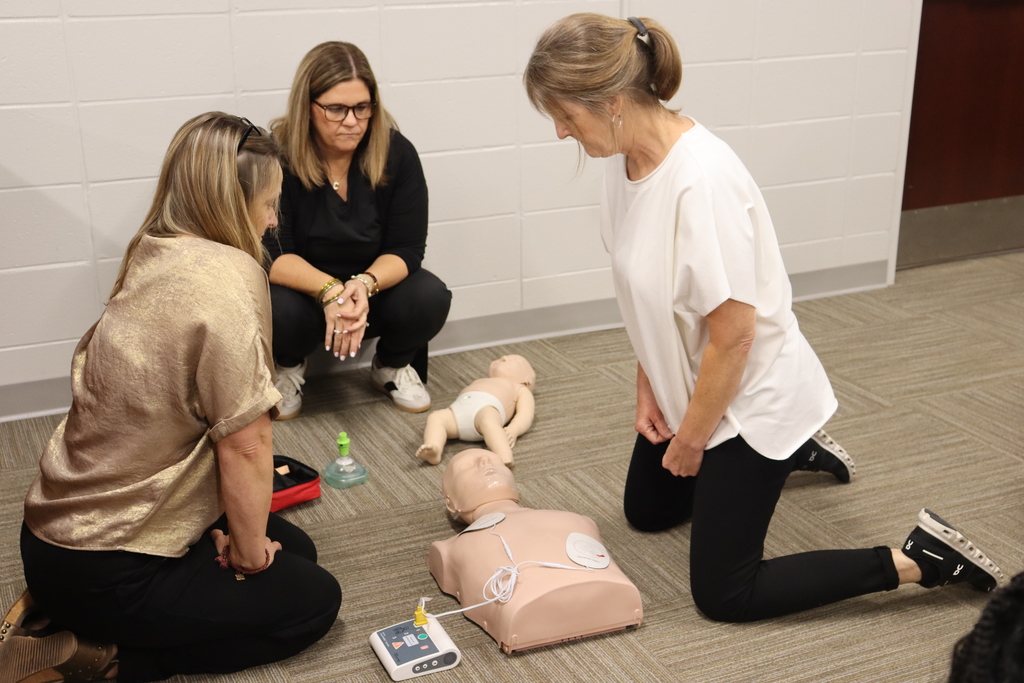 Three women practicing CPR techniques on adult and infant mannequins.