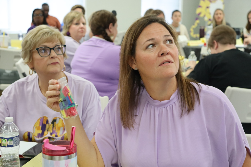 Teacher holding colorful manipulatives while listening attentively during a training session.