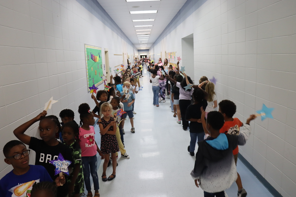 Both sides of a long hallway filled with excited students marching in a parade