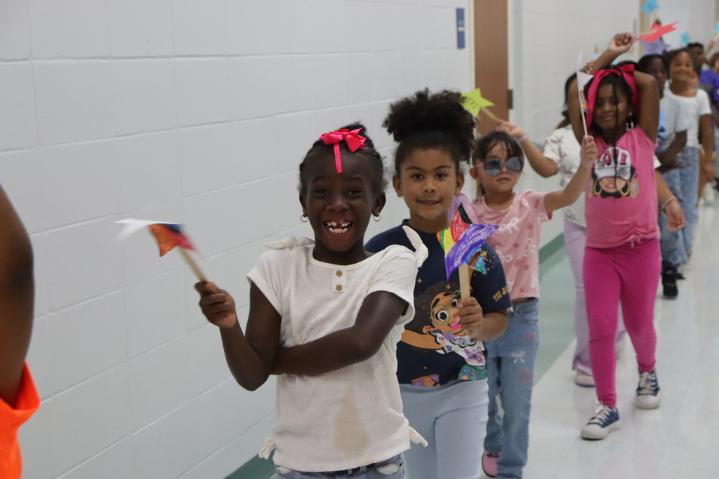 kids parade excitedly in hallways smiling at the cameras
