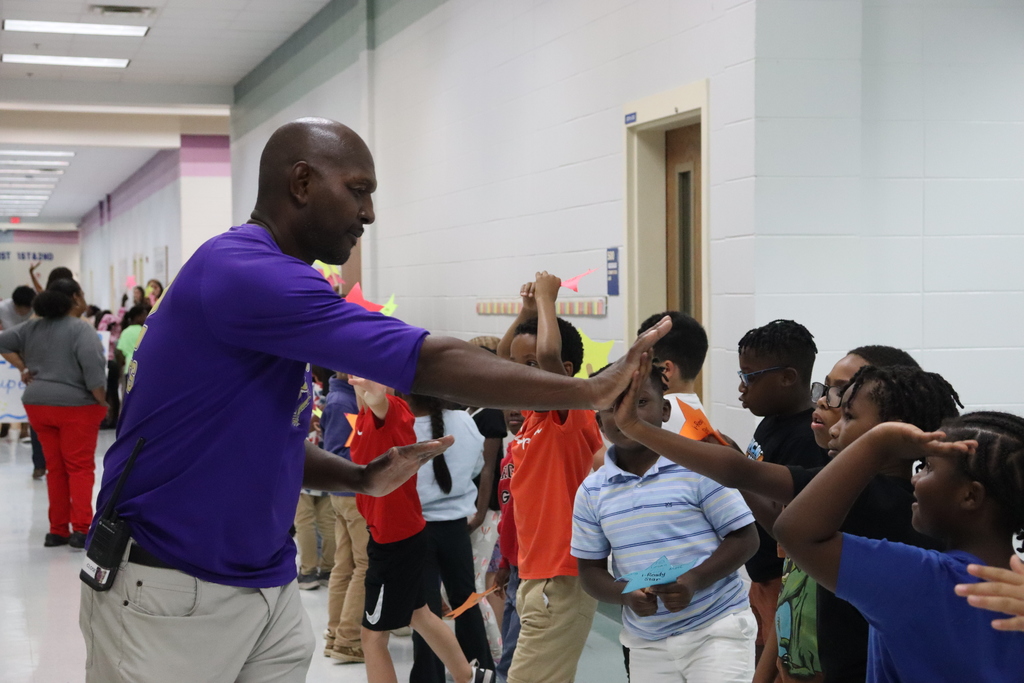 Teacher High Fives student in hallway full of kids lined up excitedly